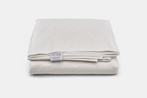 A neatly folded white Cotton Quilted Bedspread by American Blossom Linens, with a visible label, rests on a plain white background—crafted from USA grown cotton for eco-friendly luxury.
