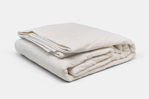 The American Blossom Linens Cotton Quilted Bedspread, made from USA-grown cotton in off-white, is neatly folded on a white background—an eco-friendly luxury ideal for any bedroom.