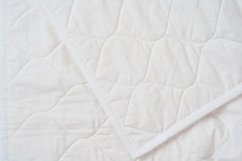 A close-up of the American Blossom Linens Cotton Quilted Bedspread highlights its diamond pattern, overlapping layers, neat stitching, and clean edges—offering USA-grown cotton comfort and eco-friendly luxury.