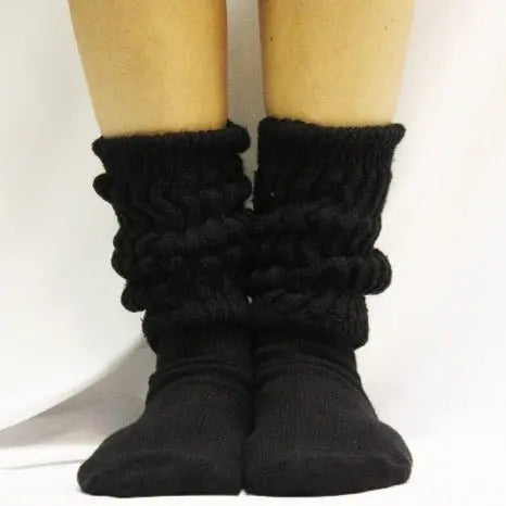 Two feet wearing Catherine Cole ULTIMATE Cotton Slouch Socks for women in black, gathered and scrunched at the ankles, shown on a white background.