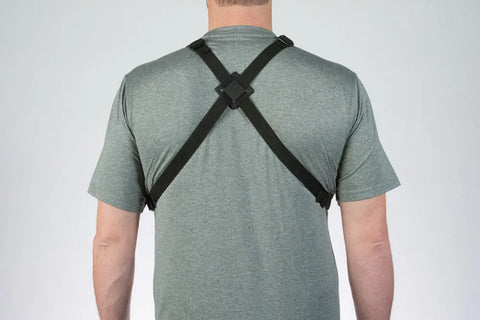 A person is seen from behind wearing a gray t-shirt and a Lone Peak Packs Universal Radio Chest Pack, featuring black adjustable straps in an X shape across the back.