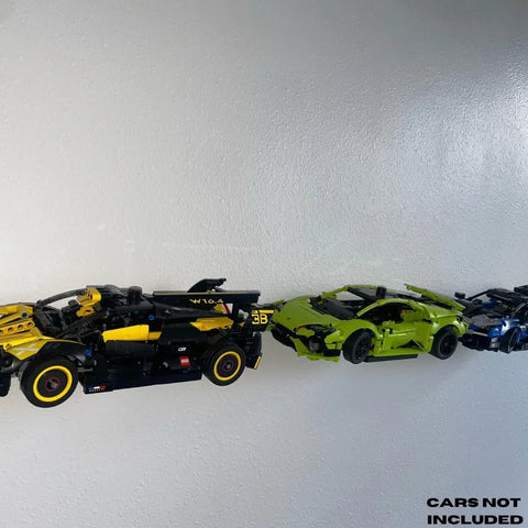 Three LEGO Technic racecars—black/yellow, green, and blue—are displayed on a Universal Wall Display by Chatelet Manufacturing. Side Profile Wall Mount fits Technic car models. CARS NOT INCLUDED appears in the bottom right corner.