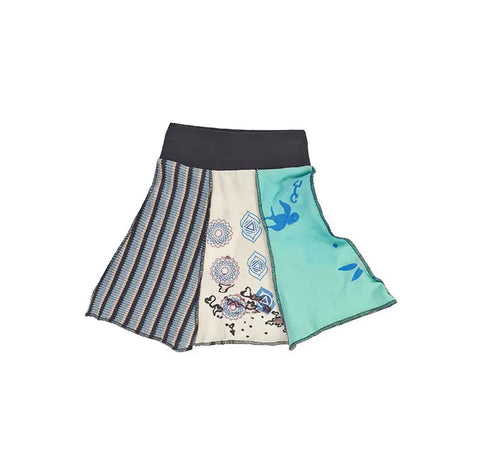 The Kids Upcycled Bell Skirt by Spiritex | Sustainable Apparel features a dark waistband and patchwork panels—blue and gray stripes, cream with geometric and floral prints, turquoise with leaf motifs—crafted from recycled fabrics with exposed seams.