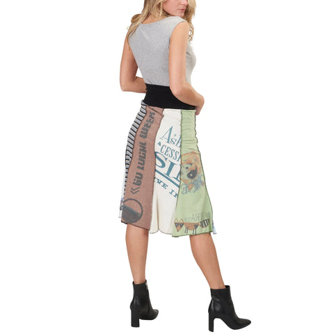 A woman stands facing away, wearing a sleeveless grey top, black ankle boots, and the Spiritex | Sustainable Apparel Upcycled Long Bell Skirt featuring colorful graphic patterns.