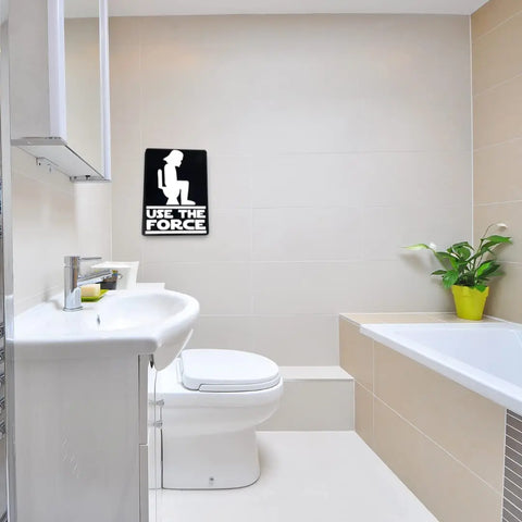 A modern bathroom with a toilet, sink, bathtub, and plant features the Chatelet Manufacturing Use the Force Bathroom Sign in black & white—a funny wall art piece perfect as quirky decor or a gag gift.