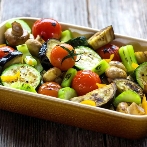 A baking dish of roasted zucchini, cherry tomatoes, mushrooms, eggplant, celery, and yellow bell pepper is seasoned with vendor-unknown’s Veggie Lovers Seasonings - 3 Pack and set on a rustic wooden table.