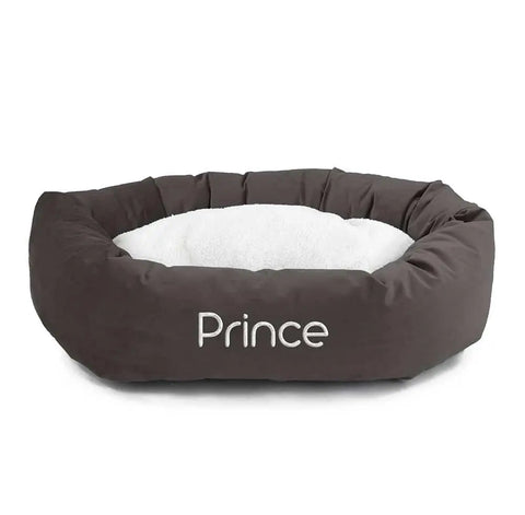The Majestic Pet Velvet Sherpa Bagel Dog Bed features a round, dark brown velvet exterior, cushioned sides, a soft white interior, and can be personalized with your pet’s name embroidered on the washable bed’s front.