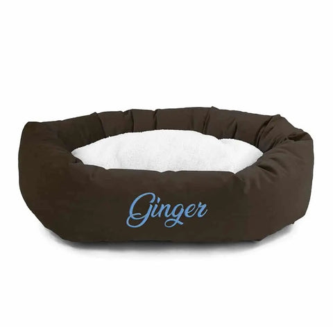 The Majestic Pet Velvet Sherpa Bagel Dog Bed features a brown velvet exterior, soft white cushion, and washable design. Personalized with the name Ginger in light blue embroidery on the front.