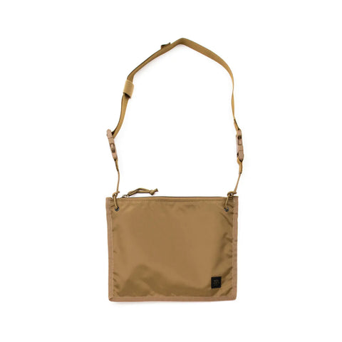 The MIS 2 Way Pouch in coyote brown is a minimalist, rectangular nylon bag featuring an adjustable strap, zipper closure, and a small black label. Sleek and functional, it’s perfect for everyday use or as a tablet clutch.