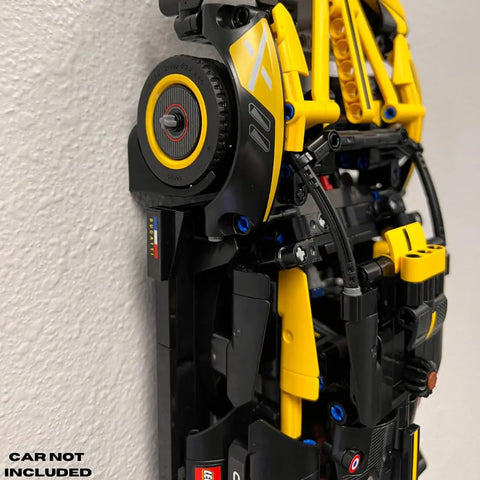 Close-up of LEGO Technic racecar parts with black and yellow pieces mounted on the Chatelet Manufacturing Vertical Collectible Car Wall Display Mount by Wheels on Wall. Text in the corner: CAR NOT INCLUDED.