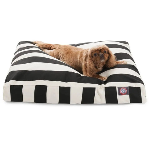 A brown dog lies on the Majestic Pet Vertical Stripe Rectangle Dog Bed, filled with premium polyester fiber fill, featuring black and white stripes, looking toward the camera.