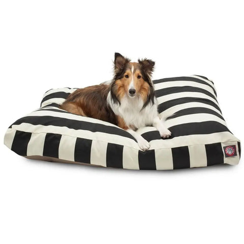 A brown and white long-haired dog is lying on a large Majestic Pet Vertical Stripe Rectangle Dog Bed with a washable black and white striped cover.