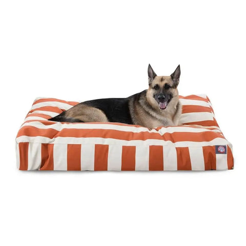 A German Shepherd rests on the Majestic Pet Vertical Stripe Rectangle Dog Bed, featuring wide orange and white stripes, a washable cover, and soft polyester fill, set against a white background.