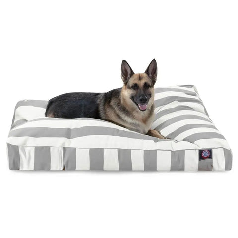 A German Shepherd relaxes on the Majestic Pet Vertical Stripe Rectangle Dog Bed, featuring gray and white stripes and premium polyester fiber fill for comfort. The washable bed is large, with the dog lying contently and facing forward with its tongue out.