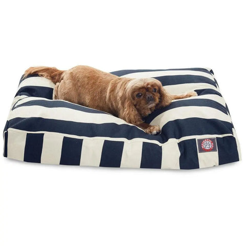 A small brown dog lies on the Majestic Pet Vertical Stripe Rectangle Dog Bed, which features bold black and white stripes, a washable cover, and polyester fill. The dog stretches out comfortably and looks toward the camera.