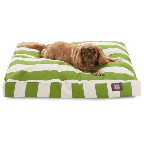 A small brown dog is lying on a green and white Vertical Stripe Rectangle Dog Bed by Majestic Pet, filled with premium polyester fiber, looking toward the camera.