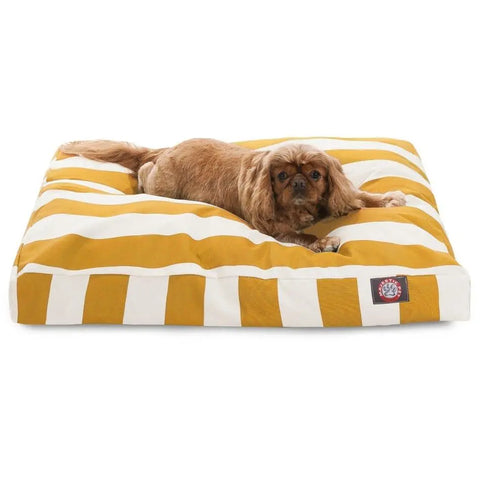 A small brown dog lies on the Majestic Pet Vertical Stripe Rectangle Dog Bed, featuring wide yellow and white stripes, a soft polyester fill, washable cover, and a fabric label on one corner for detail.