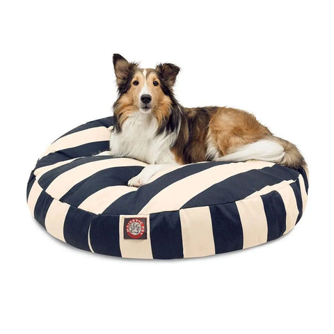 A brown and white dog lies on the Majestic Pet Vertical Stripe Round Dog Bed, which features black-and-white stripes and a removable, washable cover, set against a plain white background.