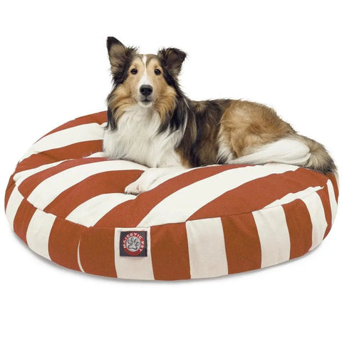 A brown, black, and white dog is lying on the Majestic Pet Vertical Stripe Round Dog Bed with wide brown and white stripes, a washable removable cover, and a logo tag on the front.