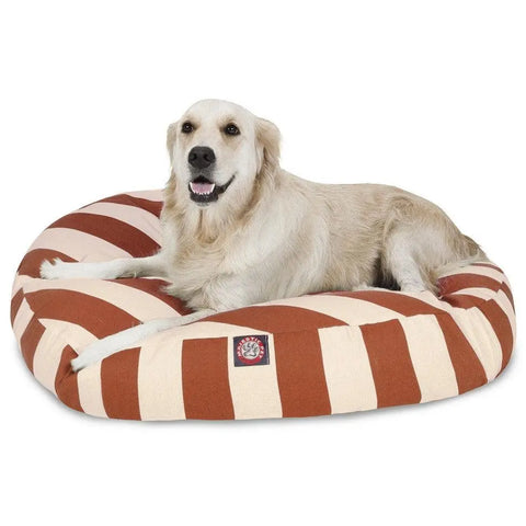 A golden retriever relaxes on the Majestic Pet Vertical Stripe Round Dog Bed with a removable cover, featuring red and beige stripes, looking at the camera with its mouth slightly open.