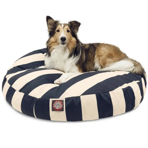 A collie lies on a Majestic Pet Vertical Stripe Round Dog Bed with black-and-white stripes, a red and white side logo, and a washable, removable cover, set against a plain white background.