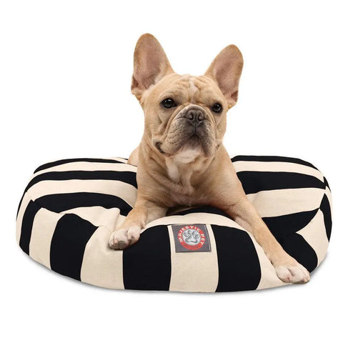 A tan French Bulldog rests on the Majestic Pet Vertical Stripe Round Dog Bed, featuring black-and-white stripes and a branded patch. Its washable, removable cover keeps it fresh as the dog looks at the camera with perked ears.