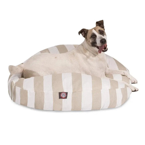 A light-colored dog with dark ears relaxes on the Majestic Pet Vertical Stripe Round Dog Bed, featuring a removable cover and beige and white stripes, set against a white background.