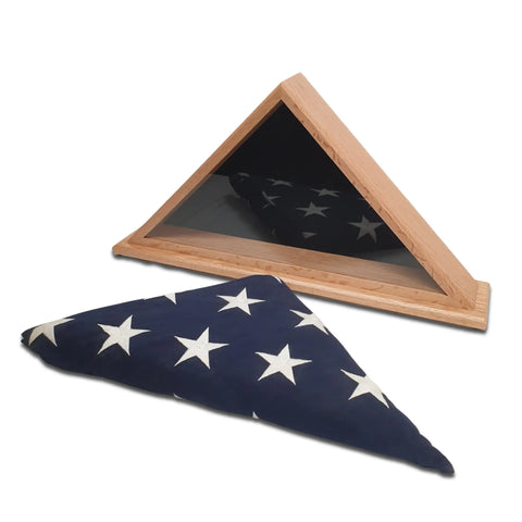 A folded American flag with white stars on blue rests before the Legacies of America Woodworking Company Oak Burial Flag Display Case, designed for a 5 x 9.5 flag.