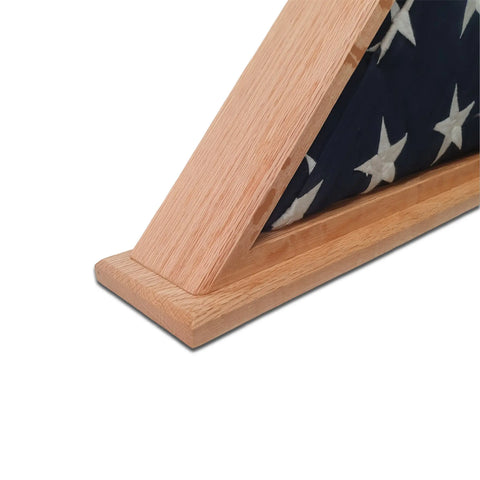 Close-up of the Legacies of America Woodworking Company Oak Burial Flag Display Case (5 x 9.5) holding a folded dark blue flag with white stars, resembling a ceremonial American flag, resting on a white surface.