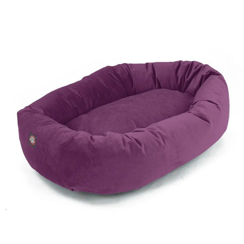 The Villa Bagel Dog Bed by Majestic Pet features an oval design in rich purple, soft Polyester Micro-Velvet, raised sides, a cushioned sleeping area, and is machine washable for easy care.