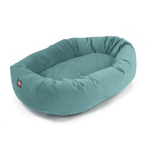 The Majestic Pet Villa Bagel Dog Bed is a soft, oval-shaped pet bed in teal blue with raised, cushioned sides and a smooth polyester micro-velvet interior, shown on a white background.