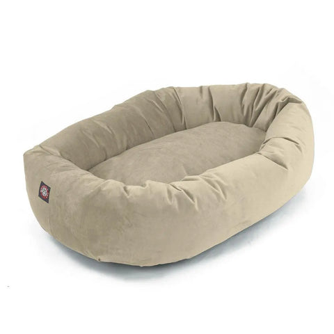 The Majestic Pet Villa Bagel Dog Bed is an oval, light beige bed with plush polyester micro-velvet sides and a cushioned base, shown on a white background.