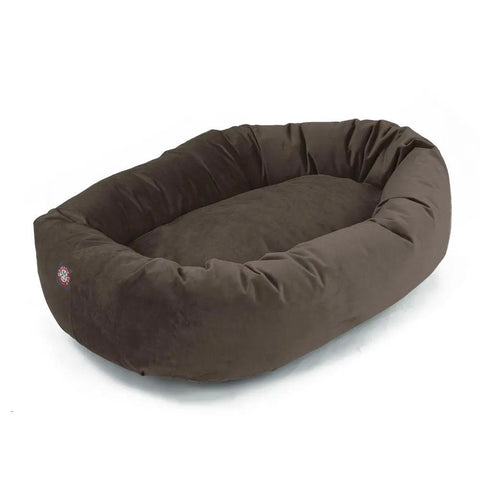 The Majestic Pet Villa Bagel Dog Bed is brown and oval-shaped with raised sides and a soft shredded memory foam interior, made from polyester micro-velvet, shown on a white background.