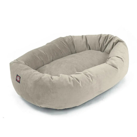 The Majestic Pet Villa Bagel Dog Bed is a light gray, oval bed with raised sides and a soft shredded memory foam interior, made from cozy polyester micro-velvet. Shown on a white background and machine washable for easy care.