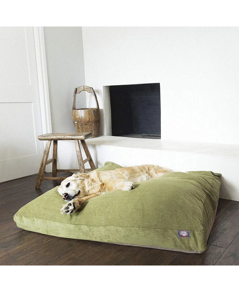 A golden retriever relaxes on the Majestic Pet Villa Rectangle Dog Bed, filled with premium polyester fiber, in front of a fireplace with a wooden stool and rustic bucket close by on a wooden floor.