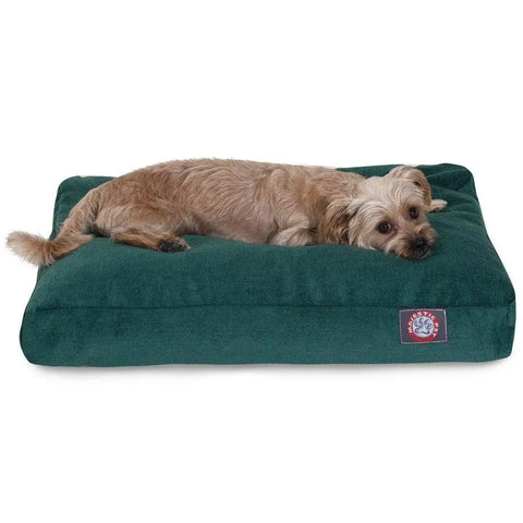 A small, light brown dog lies comfortably on a large Majestic Pet Villa Rectangle Dog Bed, filled with premium polyester fiber and featuring a sewn-on brand patch on the front.