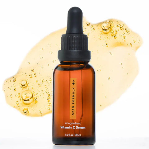 A brown glass dropper bottle of Open Formula Vitamin C Serum stands before a serum splash with visible bubbles, emphasizing its effectiveness in targeting dark spots and hyperpigmentation against a white background.