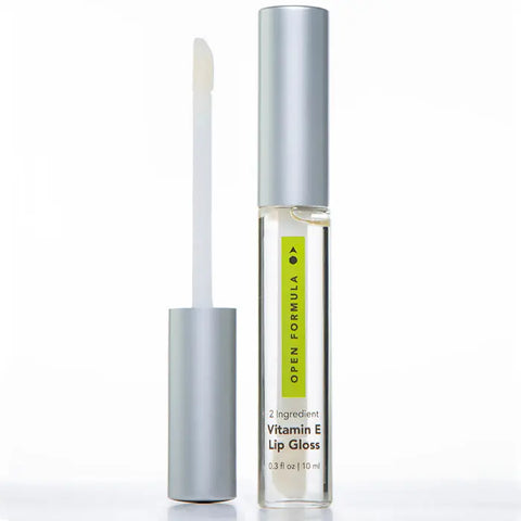 Open Formula Vitamin E Lip Gloss shown with the silver cap removed and wand applicator standing upright beside the tube. Infused with castor oil for shine and nourishment.