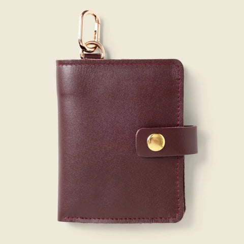 The Wallet With Snap and Key Ring - Burgundy by CASUPO is a handcrafted California leather wallet with a gold snap closure and keychain clip, shown against a light beige background.