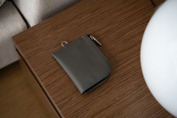 Gray leather wallet on a wooden surface with a blurred background