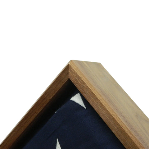 A close-up of the top corner of the Legacies of America Woodworking Company Walnut Burial Flag Display Case (5 X 9.5), showing a folded American flag with blue fabric and white stars. Crafted by veterans to honor service and sacrifice.