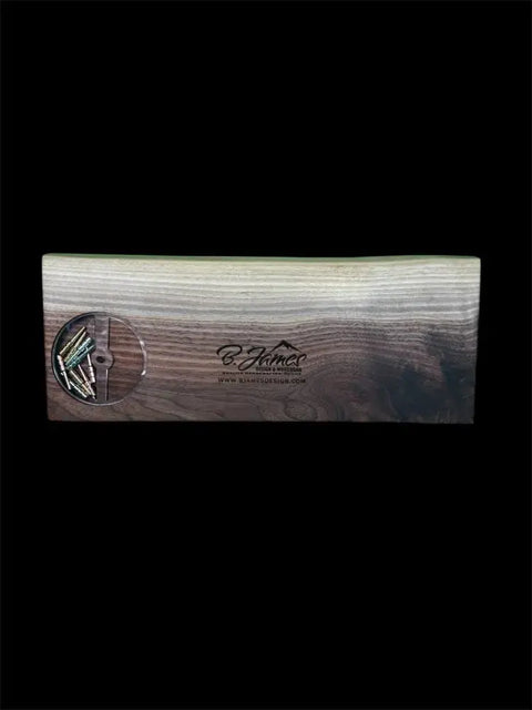 A Walnut Live Edge Cribbage Board from B. James Design & Woodwork, hand-finished in two tones. The front features the brand logo and website, plus a round transparent window revealing pegs stored inside.