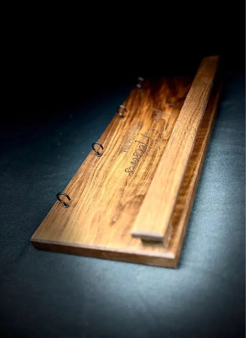 The Sunglasses and Key Rack - Walnut by B. James Design & Woodwork features a raised wooden bar, metal rings, and engraved text for elegant entryway organization, all showcasing the polished walnut grain.