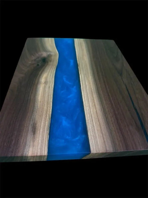 The Vivid Blue and Walnut Epoxy Serving Tray by B. James Design & Woodwork features a unique handcrafted walnut design with a striking blue epoxy river against a black background.