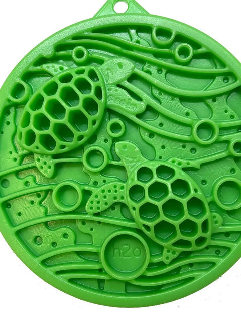 The SodaPup Water Nylon ECoin Durable Enrichment Snacking Coin is a green round plastic holder with two sea turtles in honeycomb-patterned shells, wavy lines, circular shapes, and h2o embossing. Perfect for enrichment snacks and easing problem chewing.