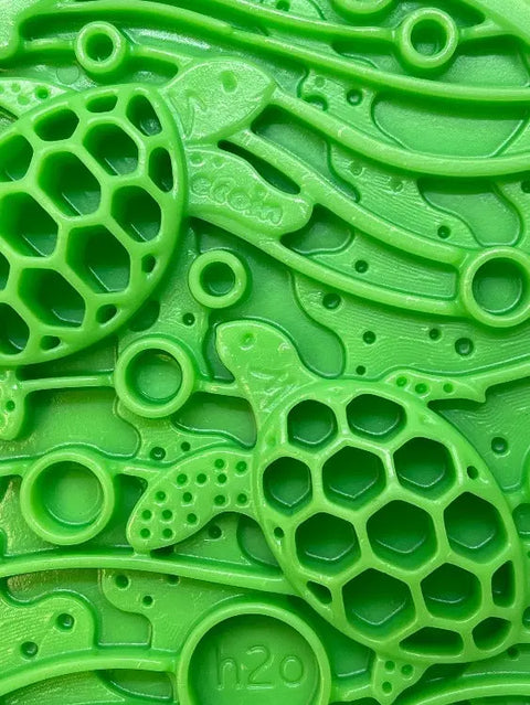Close-up of the SodaPup Water Nylon ECoin Durable Enrichment Snacking Coin: a textured green surface with two sea turtles, honeycomb shells, wavy lines, circular shapes, h2o embossed—ideal for snacks or use as a peanut butter holder.