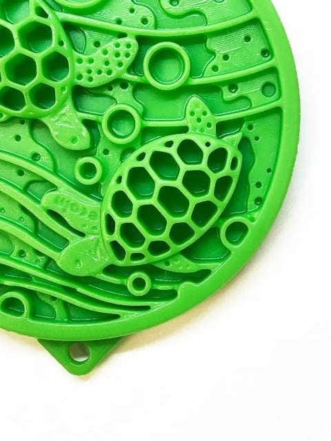 Close-up of the SodaPup Water Nylon ECoin Durable Enrichment Snacking Coin in green, featuring an embossed turtle, geometric patterns, and wavy lines—ideal for enrichment snacks and dogs who chew.