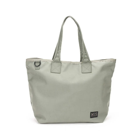 The MIS Tote Bag - Foliage is a light gray Cordura nylon tote with two handles, a metal ring by the opening, and a small black MIS patch in the bottom right corner. Water-resistant and unadorned, its ideal for everyday use.