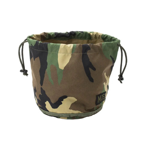 The MIS Personal Effects Bag - Woodland Camo is a round, waterproof, breathable nylon bag with green, brown, beige, and black camouflage, two side cords, and an MJS patch on the front.