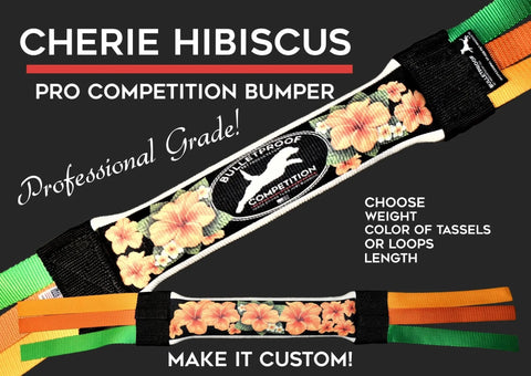 Close-up of the Bulletproof Pet Products Inc Dock Diving Bumper Tug - Competition Series Weighted Cherie Hibiscus, featuring a floral design, black background, vibrant orange and green straps, and details on pro grade quality and customizable options.